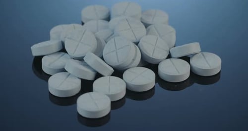 Pile of White Pills Close Up on Reflective Surface