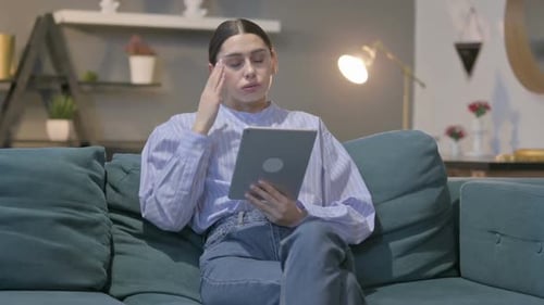 Woman Communicating on Tablet Device While Sitting on Sofa