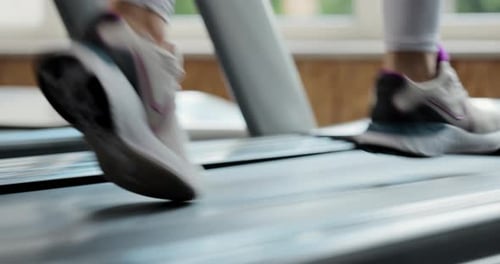 Low Angle View of Human Feet Wearing Sport Shoes Running on Electric Treadmill