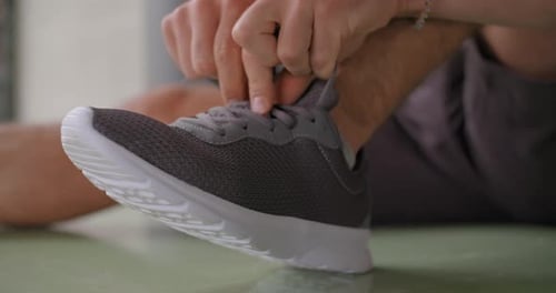 Man Tying Shoelaces on Gray and White Sneakers