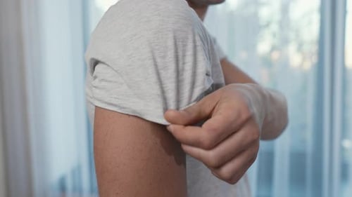 Adult With Bandage Rolls up Shirt Sleeve
