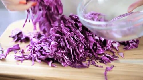 Cutting fresh red cabbage on a wood cutting board.