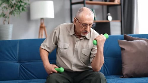 Senior Man Exercising with Dumbbells on Couch
