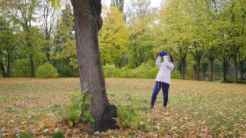 Asian woman taking a photo of view around the park in Autumn