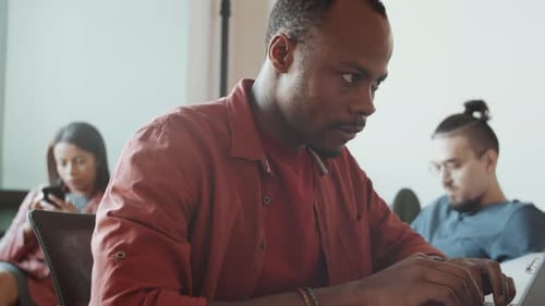 African American Man in Casualwear Working on Laptop at Office Desk
