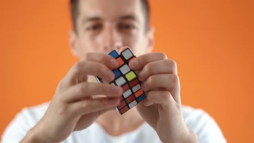 Kiev Ukraine July 30 2020 Rubik's Cube in the Hands of a Man in Studio on Orange Color Background