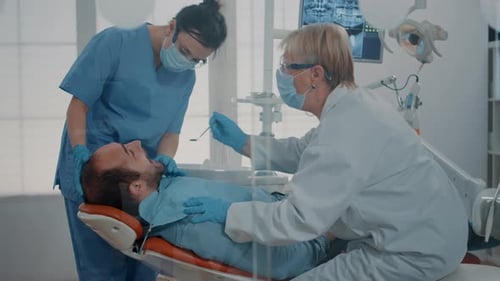 Man Receiving Dental Exam at Clinic with Two Doctors