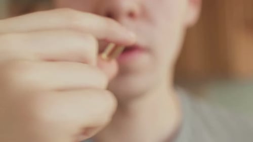 Young Adult Takes Vitamin Capsule with Water