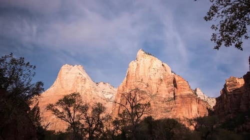 Time lapse of red cliff walls lit up as clouds move by