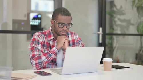 Young Adult Works on Laptop in Modern Office
