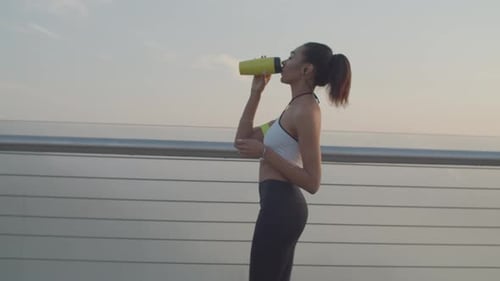 Fit Woman Drinking Water on City Walkway
