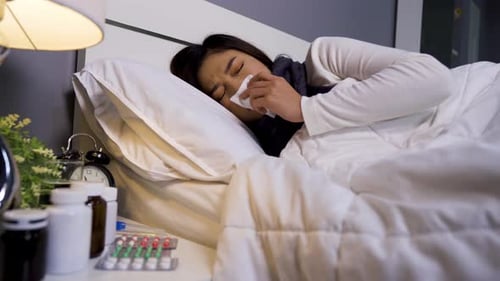 femme malade ayant froid et éternuant au lit