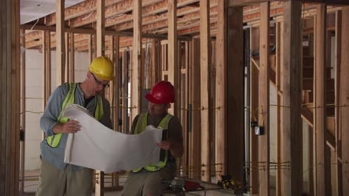 Construction Workers Reviewing Blueprint in Unfinished Building