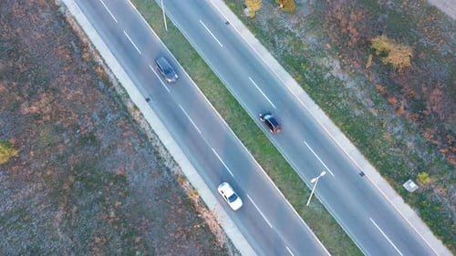 Traffic of motor vehicles on a two way four lane street passing through an uncultivated field