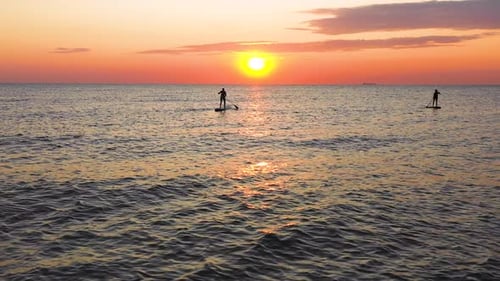 Boy nad girl enjoing on Paddle board on summer day. Sea side sunset