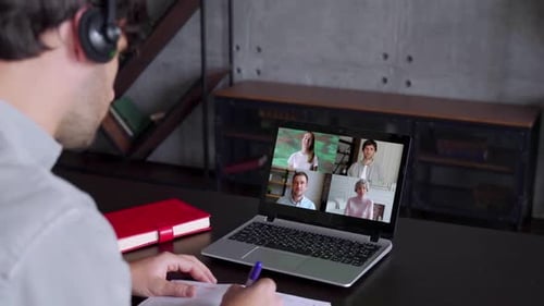 Vue arrière d'un homme parlant à l'aide d'une conférence par webcam sur un ordinateur portable avec divers collègues, une employée