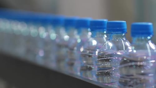 Closeup of PET Bottles Moving Along a Conveyor Line of Industrial Equipment