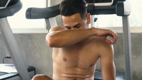Tired Man Wiping Sweat While Relaxing After Exercising at the Gym
