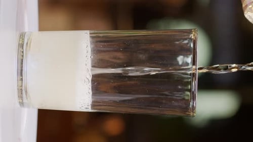 Gelbes Erfrischungsgetränk in ein Glas gießen, Nahaufnahme in Zeitlupen-Aufnahme