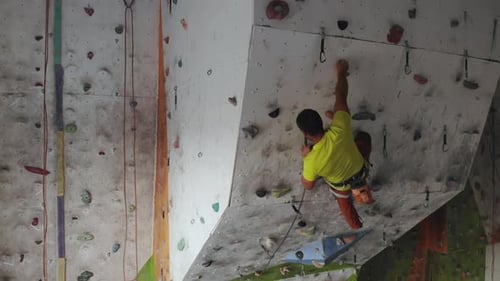 Young Man Rock Climber is Climbing At Inside Climbing Gym