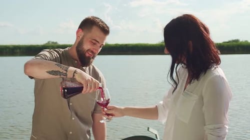 Zeitlupenaufnahme eines Mannes, der im Glas einer Frau auf Rotwein gießt