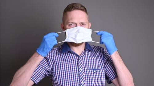 Man Putting on Face Mask with Blue Gloves
