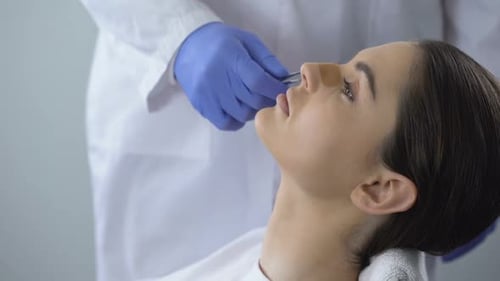 Doctor Removes Bandage from Woman's Nose
