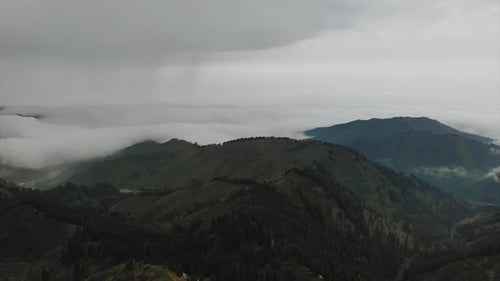 Aerial Mountain landscape clouds covered with tree forest and roads