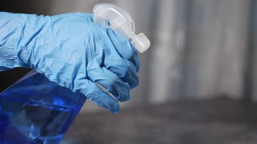 Hand Using Spray Bottle With Blue Liquid