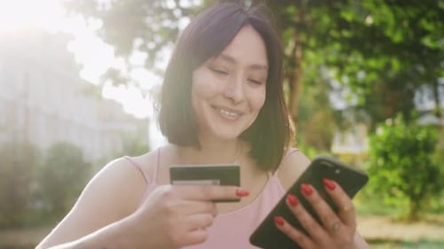 Woman Using Phone and Credit Card Outdoors