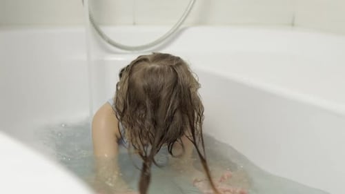 Adorable Girl Plays in a Bathtub