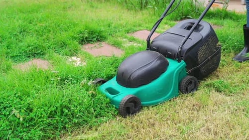 worker using a lawn mower cutting grass at home