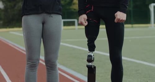 Crop View of Unknown Woman and Disabled Man with Prosthetic Leg Standing at Sports Field