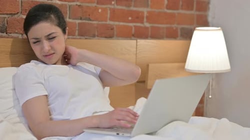 Woman Using Laptop in Bed Experiencing Neck Pain