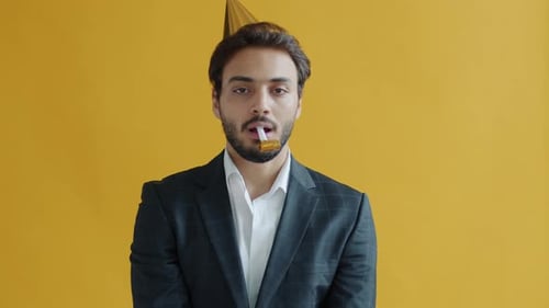 Man Wearing Party Hat Blows Party Horn