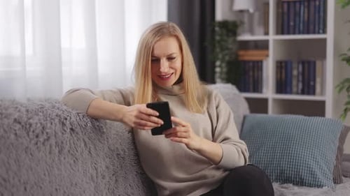 Blonde Woman Using Phone While Relaxing on Couch