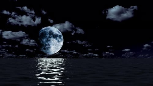 The full moon shines over the night sea and clouds