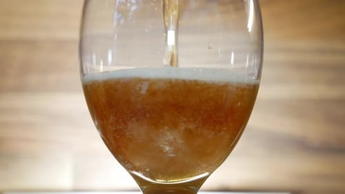 Pouring fresh and tasty dark beer into glass, close up view