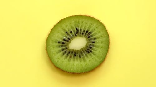 Slice of Kiwifruit Rotating Top View on Yellow Background