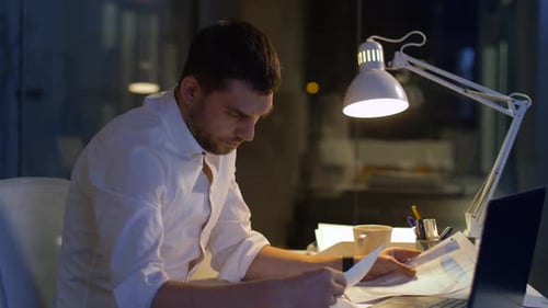 Geschäftsmann mit Akten und Laptop bei Nacht 12