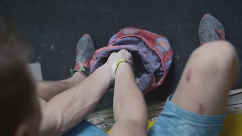 Male Rock Climber Uses Magnesia on the Climbing Wall