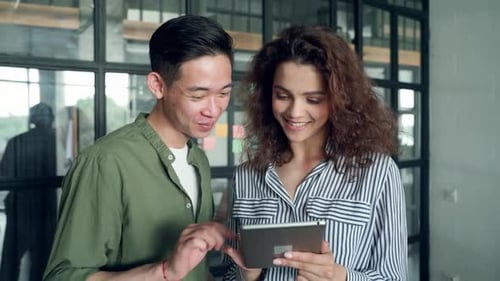 Multicultural Coworkers Using Tablet Device Together in Modern Office