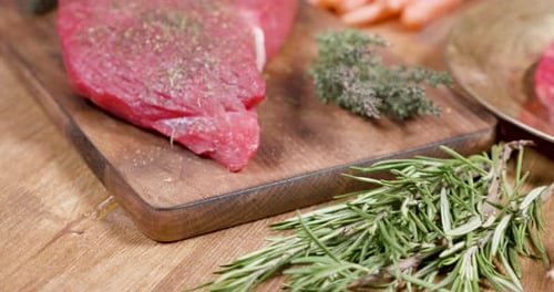 Raw Steak with Rosemary and Onion on Table