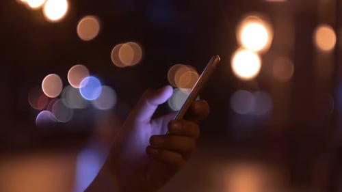 Hand Tapping Smartphone Screen at Night