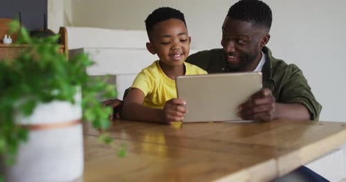 Padre e hijo afroamericanos usan juntos una tableta digital