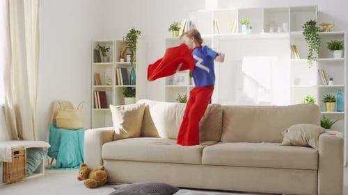 Child in Superhero Costume Jumping on Couch
