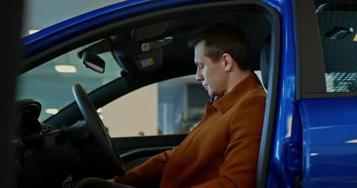 Man Sits in a Car at Dealership