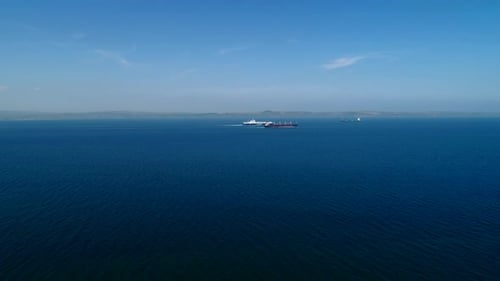 Cargo Ship Travels Across the Ocean on Sunny Day
