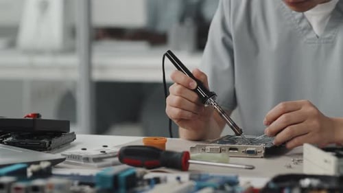 Person Soldering Circuit Board at Electronics Workplace