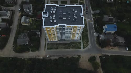 City block. Modern multi-storey buildings among cottages. Flying at dusk at sunset.